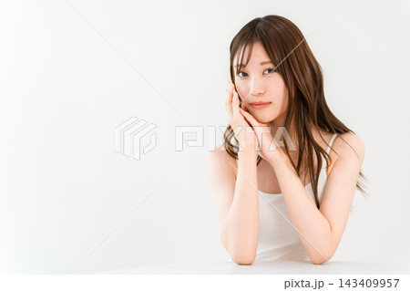 頬に手を添える若い女性。透明感のある肌とナチュラルメイクの美容イメージ 143409957