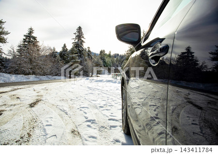 Winter travel. Car stands parked on snowy road surrounded by frosted trees 143411784