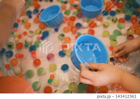 カラフルなスーパーボールをすくう子どもの手 143412361
