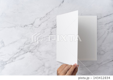 Top view sequence from open to close blank white greeting card mockup on marble background with copy space : hand opening a blank white folded greeting card Top view sequence from open to close blank white greeting card mockup on marble background with copy space : hand opening a blank white folded greeting card 143412834