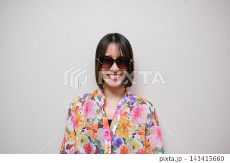 花柄のシャツを着てサングラスをかけた笑顔の女性の白背景のポートレート 143415660