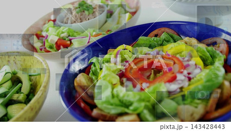 Showing blue salad bowl holding lettuce,tomato,onion,croutons on white tabletop with two bowls 143428443