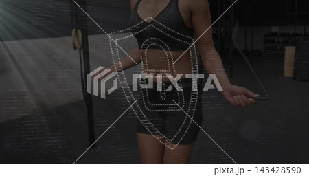 Jumping mid-adult woman in dark sportswear, gripping jump-rope in dim gym with rig, shield overlay Jumping mid-adult woman in dark sportswear, gripping jump-rope in dim gym with rig, shield overlay 143428590