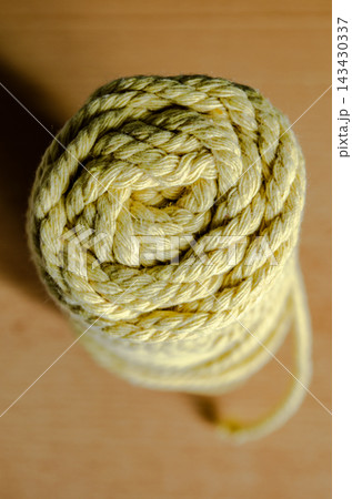 Coiled yellow rope on a wooden surface 143430337