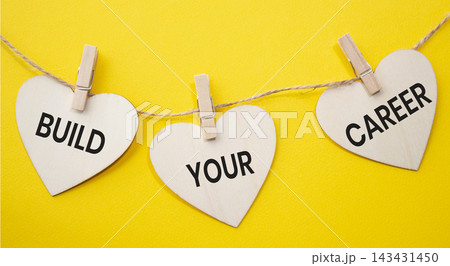 Build Your Career text on wooden heart tags hanging on rope with clothespins over yellow background. Professional growth and career development concept with copy space. Build Your Career text on wooden heart tags hanging on rope with clothespins over yellow background. Professional growth and career development concept with copy space. 143431450