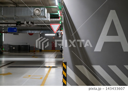 Empty Underground Parking Garage Interior With Concrete Pillar Marked A And Directional Signs Empty Underground Parking Garage Interior With Concrete Pillar Marked A And Directional Signs 143433607