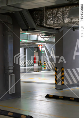 Empty Modern Underground Parking Garage Interior With Concrete Columns, Safety Markings and Directional Signs 143433608