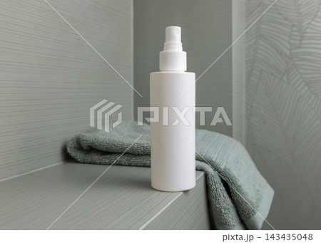 White cosmetic spray borttle mockup on light green towel in bathroom, unbranded packaging 143435048