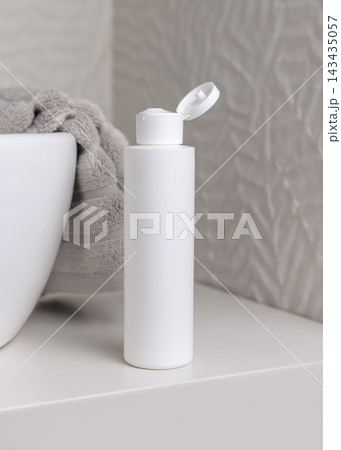 White flip top bottle mockup near grey towel in beige bathroom, unbranded cosmetic packaging White flip top bottle mockup near grey towel in beige bathroom, unbranded cosmetic packaging 143435057