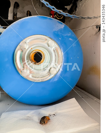 Blue pressure expansion vessel with an open steel flange and rust residue after removal. Worn tank of a water heating system Blue pressure expansion vessel with an open steel flange and rust residue after removal. Worn tank of a water heating system 143435346