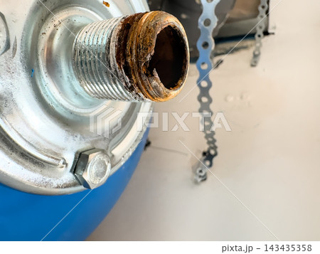 Macro view of a corroded threaded connector on a blue expansion vessel. Rust on the thread that caused a leak 143435358