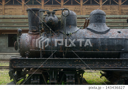 The historical old steam locomotive parked next to a building The historical old steam locomotive parked next to a building 143436827