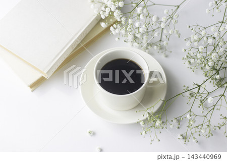 閉じた本とブラックコーヒー、かすみ草のある明るいテーブル 閉じた本とブラックコーヒー、かすみ草のある明るいテーブル 143440969