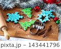 Baking holiday cookies and decorating them with colorful icing and sprinkles in a festive kitchen 143441796