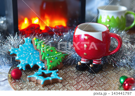Winter holiday scene with festive decorations, cookies, and warm beverage in a colorful mug 143441797