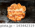 鉄板の上で香ばしく焼き上げられたミックス豚玉、豚肉が乗ったお好み焼き 143442319