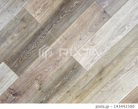 Diagonal wood floor planks texture with natural grain patterns. Modern laminate flooring in neutral beige, grey, and brown tones for interior design background. Close-up of rustic timber surface. Diagonal wood floor planks texture with natural grain patterns. Modern laminate flooring in neutral beige, grey, and brown tones for interior design background. Close-up of rustic timber surface. 143442380