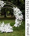 Elegant white flower arrangement on circular metal arch. 143442392