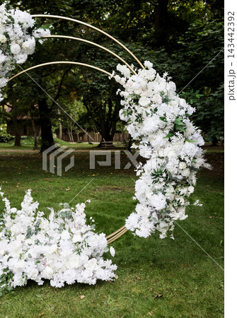 Elegant white flower arrangement on circular metal arch. 143442392
