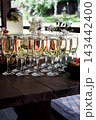 multiple champagne flutes with sparkling wine lined up on a dark wooden table 143442400