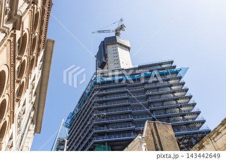 Low angle view of a modern skyscraper under construction with a crane Low angle view of a modern skyscraper under construction with a crane 143442649