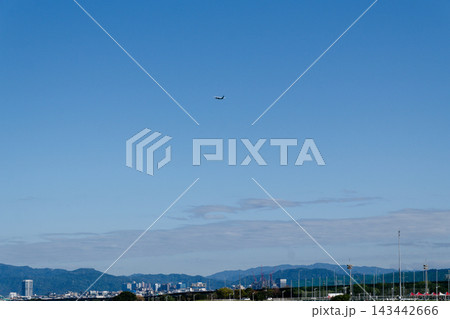 Small airplane flying in clear blue sky above a riverside city and green hills 143442666