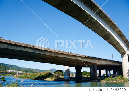 Wide view of two elevated bridges crossing a river under clear blue sky Wide view of two elevated bridges crossing a river under clear blue sky 143442669
