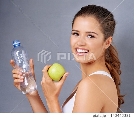 Water, apple and portrait of happy woman on gray background for training, exercise and workout. Fitness, studio and person with fruit for vitamins, diet and detox with health, wellness or lose weight 143443381