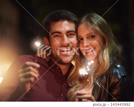 Portrait, happy couple and sparklers at night for party, celebration and event together outdoor in city with light. Face, man and woman with fireworks on holiday, romantic date or laugh on vacation 143443992