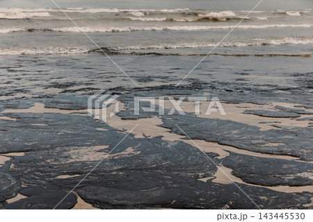 Oil fuel contamination spreads across a beach, creating a serious environmental pollution disaster 143445530