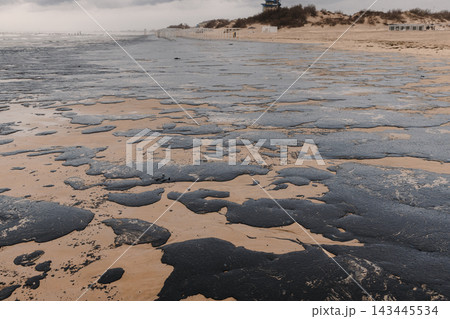 Polluted ocean shoreline with oil fuel residue covering rocks and sand after an apparent oil spill 143445534