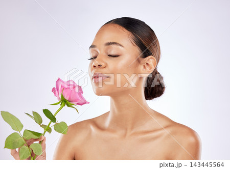 Rose, scent and woman in beauty with flower for healthy skincare on studio background. Floral, fragrance and girl smell perfume of plant blossom with natural glow on face from cosmetics in spring 143445564