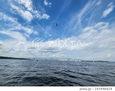 青空と雲の下を飛ぶ飛行機と都市を結ぶ大橋、海から望む風景 青空と雲の下を飛ぶ飛行機と都市を結ぶ大橋、海から望む風景 143446824