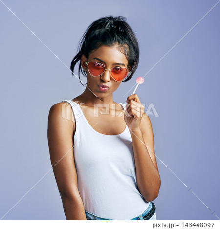 Girl, portrait and funky heart sunglasses as gen z on blue background for fashion, style and freedom. Edgy, female person and happiness with candy in playful, pouting for kiss in studio backdrop Girl, portrait and funky heart sunglasses as gen z on blue background for fashion, style and freedom. Edgy, female person and happiness with candy in playful, pouting for kiss in studio backdrop 143448097