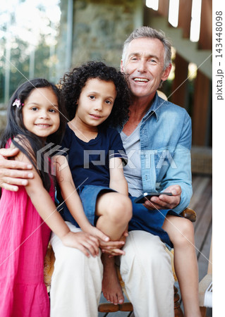 Grandkids, portrait and man on sofa with smartphone, internet video or online movie. Smile, grandpa and technology for entertainment, sharing and comfort for family care visit together with children 143448098