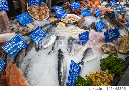 Various fresh seafood and raw fish arranged on ice with price tags at market stall 143448206