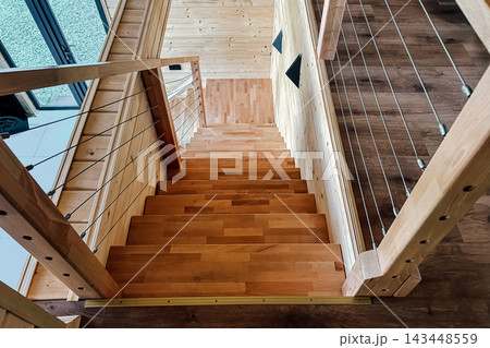 Wooden staircase leads down to modern living area in a cozy home setting Wooden staircase leads down to modern living area in a cozy home setting 143448559