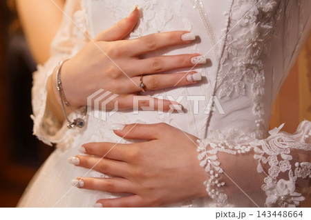Closeup of Bride Hands with Wedding Rings, White Lace Dress Details and Elegant Manicure Closeup of Bride Hands with Wedding Rings, White Lace Dress Details and Elegant Manicure 143448664