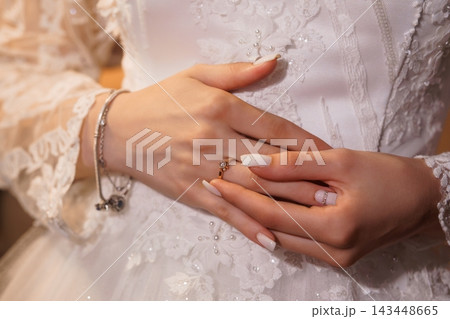 Closeup of bride's hands displaying diamond wedding rings on lace wedding dress with manicured nails Closeup of bride's hands displaying diamond wedding rings on lace wedding dress with manicured nails 143448665