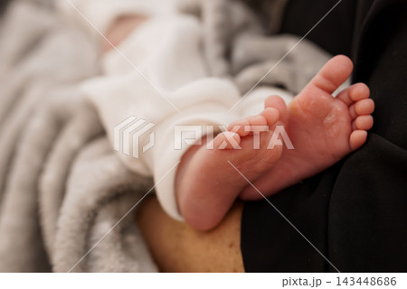 Infant Feet Resting on Adult Lap Under Soft Blanket Close-Up Infant Feet Resting on Adult Lap Under Soft Blanket Close-Up 143448686
