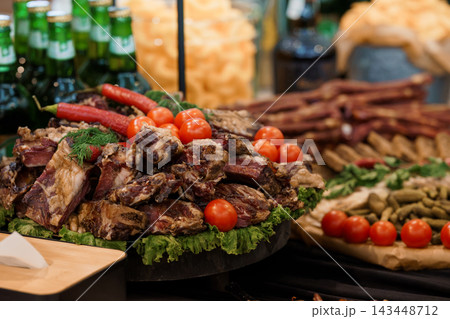 Gourmet grilled meat platter with fresh cherry tomatoes chili peppers lettuce greens appetizer spread event catering party display Gourmet grilled meat platter with fresh cherry tomatoes chili peppers lettuce greens appetizer spread event catering party display 143448712