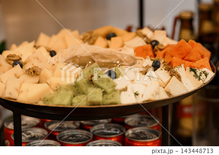Assorted cheese platter with fruits nuts olives served on metal tray with drinks below at social gathering or party catering setup Assorted cheese platter with fruits nuts olives served on metal tray with drinks below at social gathering or party catering setup 143448713