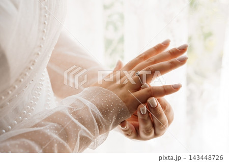 Bride admiring diamond engagement ring in lace wedding dress Bride admiring diamond engagement ring in lace wedding dress 143448726