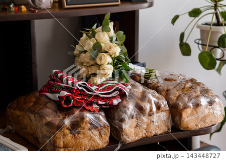 Traditional Easter Bread Loaves with White Rose Bouquet on Wooden Table with Red Embroidered Napkin at Home Traditional Easter Bread Loaves with White Rose Bouquet on Wooden Table with Red Embroidered Napkin at Home 143448727
