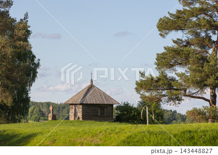 A tranquil summer countryside landscape featuring a small historic wooden chapel A tranquil summer countryside landscape featuring a small historic wooden chapel 143448827
