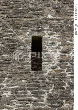 Vertical photo of weathered stone wall featuring a narrow window of Izborsk Fortress 143448835