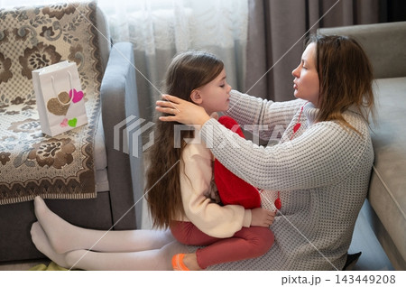 A loving mother comforts her young daughter, sharing a tender moment of connection and affection. 143449208