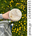 Overhead shot of a takeaway coffee cup held above yellow wildflowers for lifestyle background and social media banner design 143449355