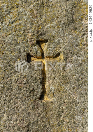 Close-up of an ancient stone cross carved into a weathered rock surface Close-up of an ancient stone cross carved into a weathered rock surface 143449626