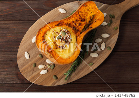 Delicious baked pumpkin filled with creamy soup, sprinkled with seeds and herbs Delicious baked pumpkin filled with creamy soup, sprinkled with seeds and herbs 143449762